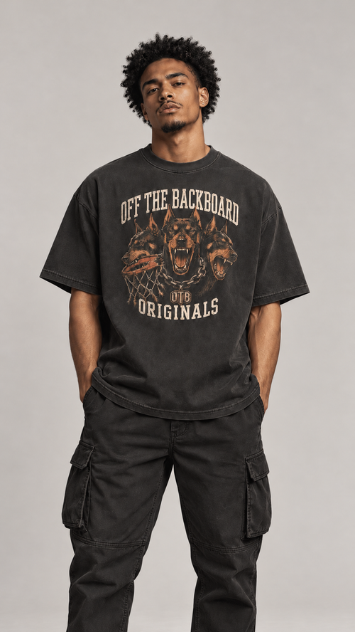 A man wearing a faded black graphic t-shirt with 'OFF THE BACKBOARD ORIGINALS' and a dog graphic, paired with black cargo pants, against a neutral gray background.