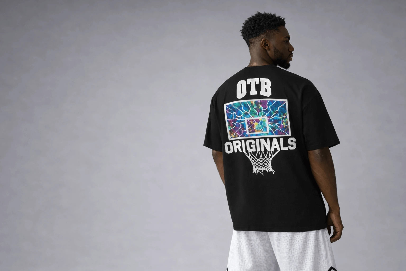 Person wearing a black t-shirt with 'OTB Originals' branding on the back, standing against a gray background.
