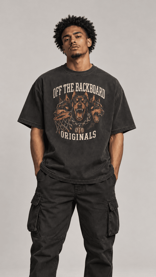 A man wearing a faded black graphic t-shirt with 'OFF THE BACKBOARD ORIGINALS' and a dog graphic, paired with black cargo pants, against a neutral gray background.