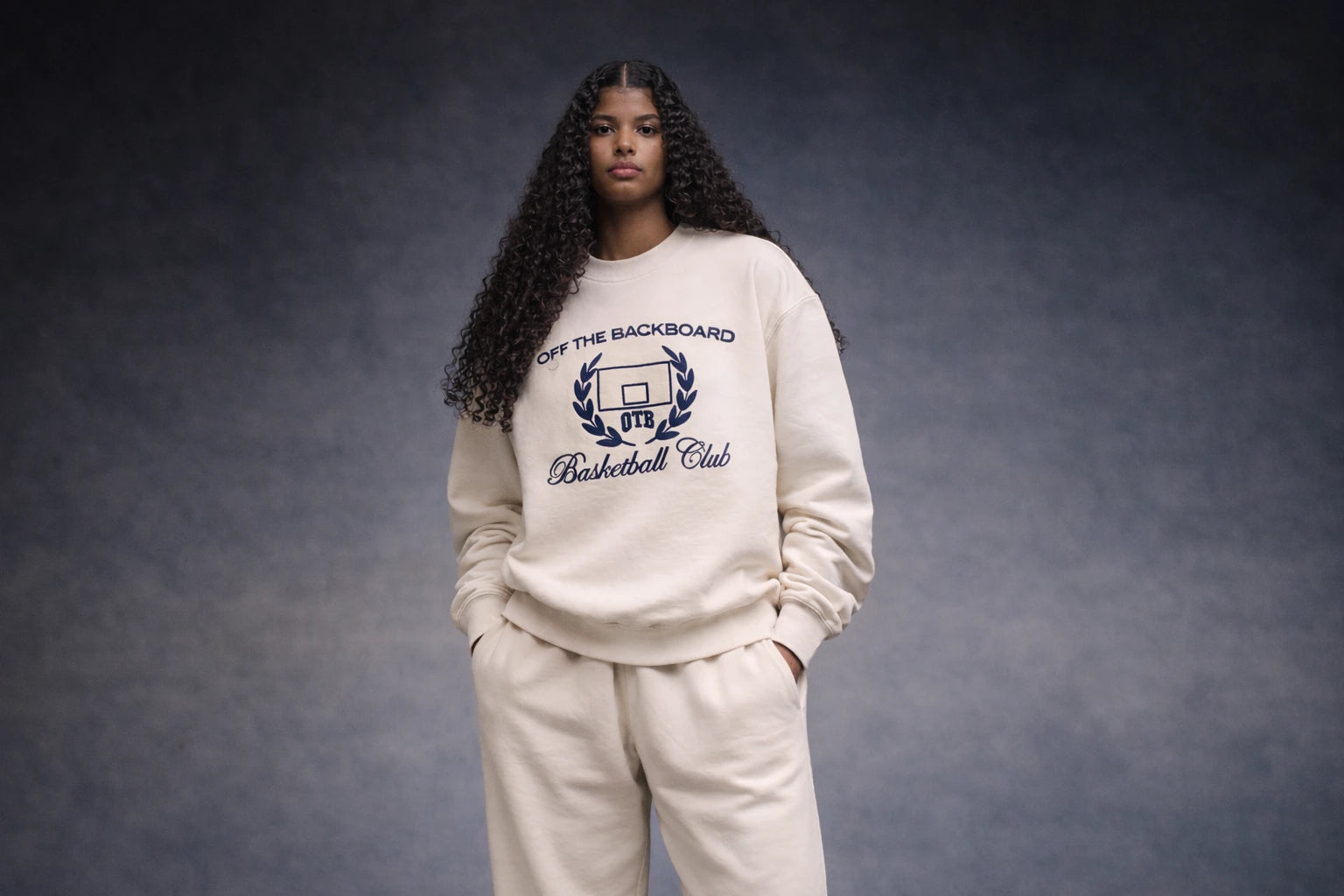 Person wearing a beige sweatshirt with text and graphics on a dark background