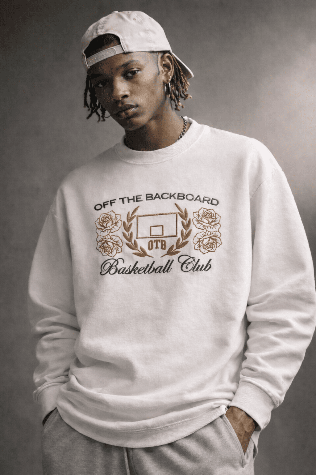 Person wearing a white sweatshirt with 'Off the Backboard Basketball Club' design on a gray background