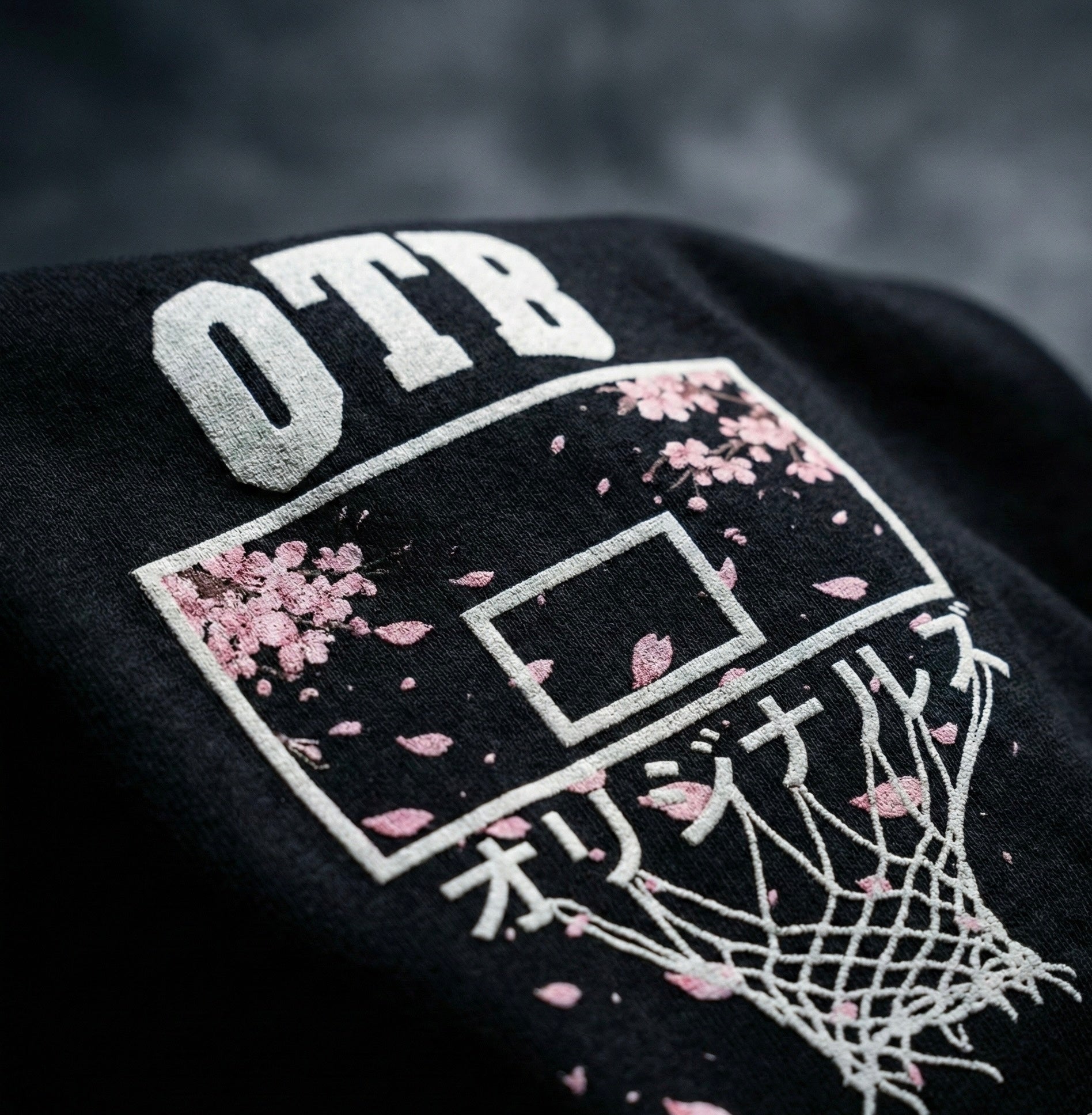 Black sweatshirt with 'OTB' and cherry blossom design on a dark background