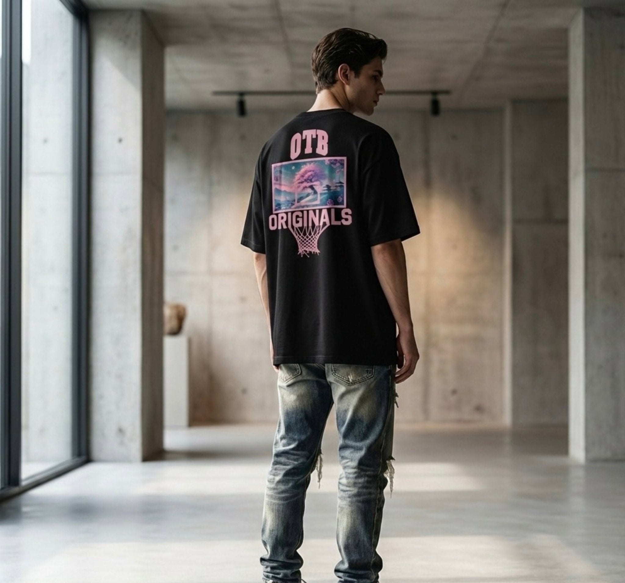 Person wearing a black t-shirt with 'Originals' design in a modern indoor setting