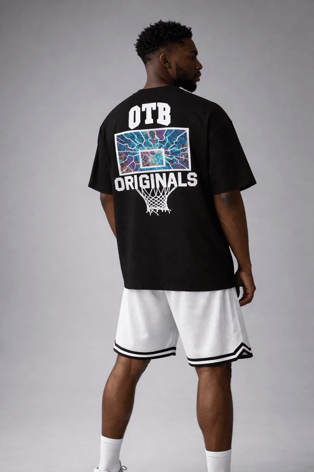 Athlete wearing a black 'OTB Originals' t-shirt with a colorful graphic on the back, standing against a gray background.