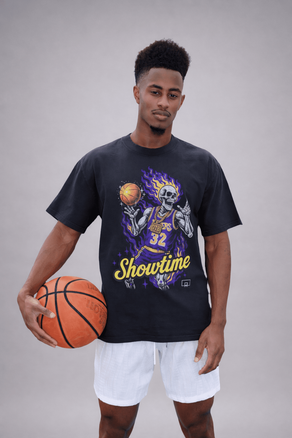 Man holding a basketball wearing a black t-shirt with a graphic design on a gray background