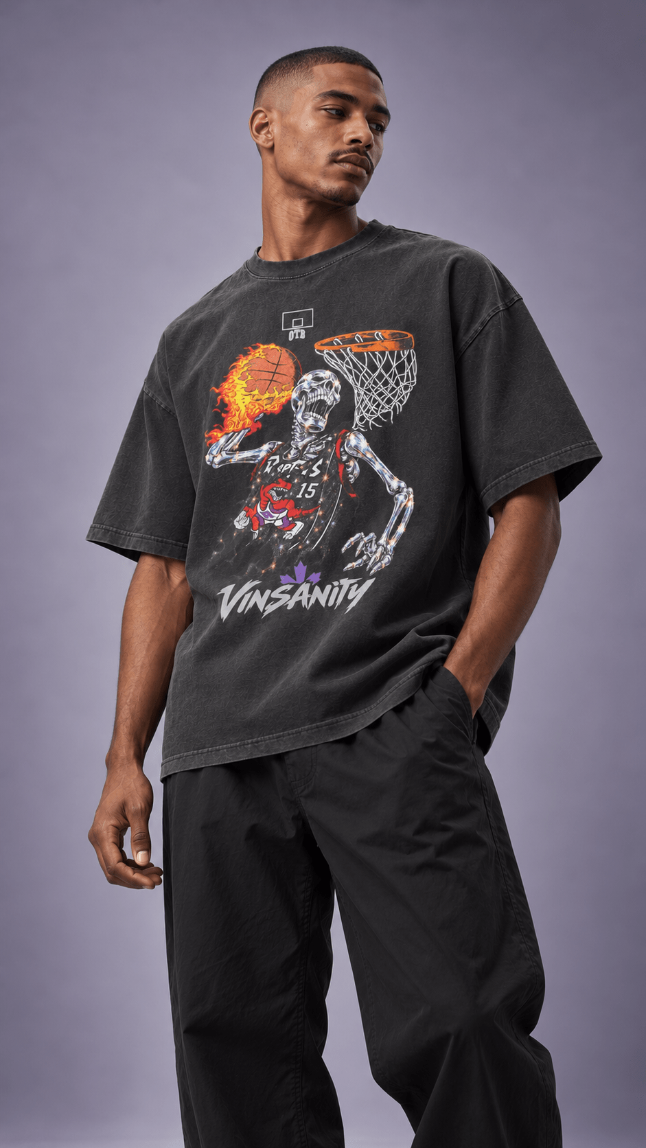A man wearing a faded black graphic t-shirt with a skeleton basketball player design and the word 'VINSANITY' printed on the front, paired with black sweatpants, against a solid gray studio background.